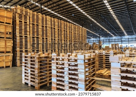 Explore the organized chaos of a bustling warehouse, where towering stacks of wooden pallets are meticulously arranged, ready for transportation and logistics