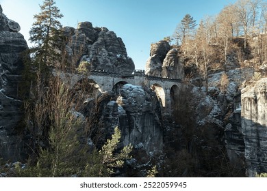 Explore the stunning Badlands of Swiss Saxony with a historic stone archway embraced by towering rock formations in winter sunlight - Powered by Shutterstock