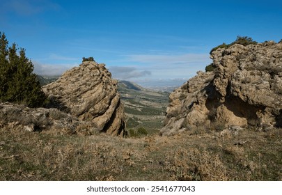 Explore this breathtaking mountain landscape featuring rugged rocky formations with a lush green valley below under a clear blue sky. - Powered by Shutterstock