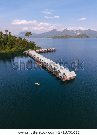 Explore the tranquil waters of Cheow Lan Lake in Khao Sok, Thailand. floating bungalow rafts with tourist in a kayak