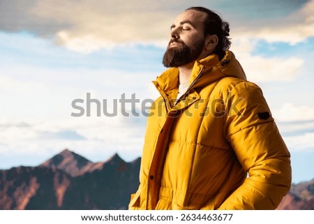 Explorer on a mountain peak taking in the fresh air and panoramic scenery. Climber nature lover admires the stunning landscape of rugged peaks and vast sky, adventure and sightseeing.