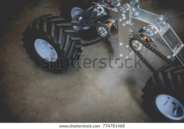 Explorer robot on four wheels with copy space for\
text. Close up of automobile robot rescues on dark floor with\
vintage effect.