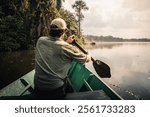 Explorer rowing on a canoe in the amazon rainforest during sunset