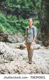 Explorer Young Woman Wearing In Cargo Pants And Plaid Shirt Standing On Rocky Stone Outdoor, Looking At Camera.