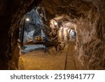 Exploring an abandoned underground mine in the mountains with machinery and tracks