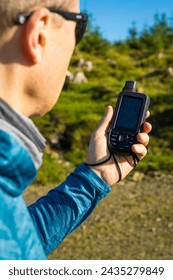 Exploring the mountains, a middle-aged traveler using a handheld GPS device to find his way