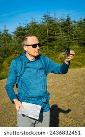 Exploring the mountains, a middle-aged traveler using a compass to find his way