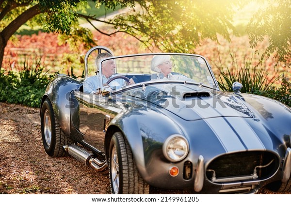 Exploring the outdoors in\
style. Shot of a happy senior couple enjoying a roadtrip in a\
convertible.
