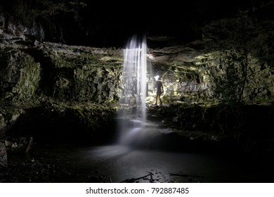 Exploring and Standing Behind a Waterfall at Night, in a Canyon with Cliff Side and Water Illuminated