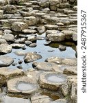 Exploring the unique rock formations and tranquil pools at Giants Causeway in Northern Ireland during a cloudy day