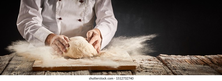 Explosion of flour suspended in the air in a pizzeria kitchen as the chef prepares a portion of dough for the crust in a rustic panorama banner with copy space