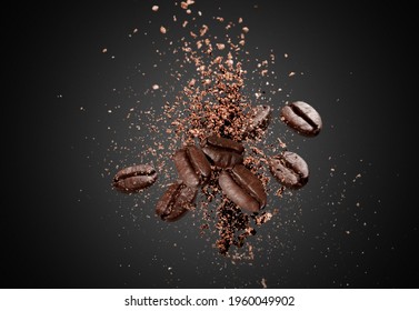 Explosion of ground coffee with roasted beans on dark background