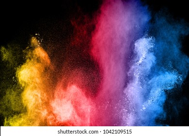 The explosion of multi colored powder. Beautiful rainbow color powder fly away. The cloud of glowing color powder on black background