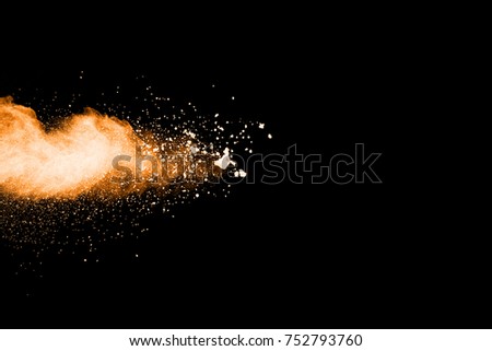 Explosion of orange and brown dust on black background.