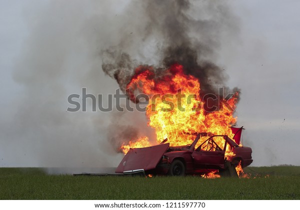 explosion red car on a green lawn cloudless sky\
fire sparks smoke\
explosion