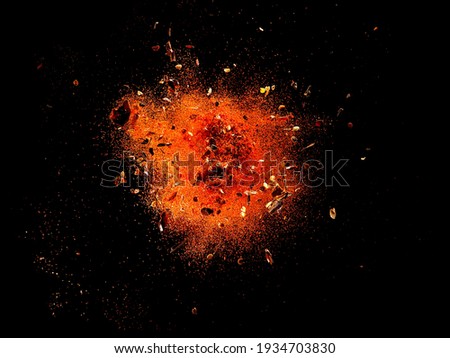 Explosion of red cayenne pepper with flakes and seeds on black background