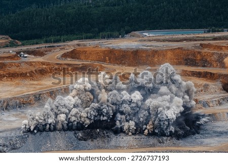 Explosive activity in open pit mine with dramatic dust cloud formation.