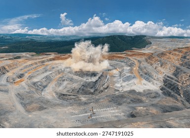 Explosive activity in vast open pit mine with dust cloud and terraced layers, Aerial panorama of industry landscape.