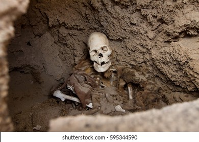 Exposed Human Skeleton And Skull In A Burial Mound In The Andes Still Partly Embedded In The Hardened Clay And Rock Viewed Through A Hole In The Wall Of The Chamber