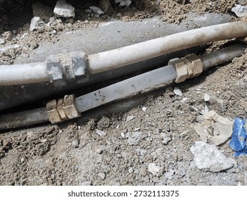 Exposed underground pipe section with connected fittings in soil trench
