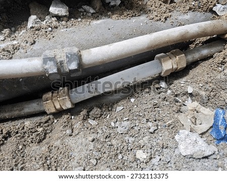 Exposed underground pipe section with connected fittings in soil trench

