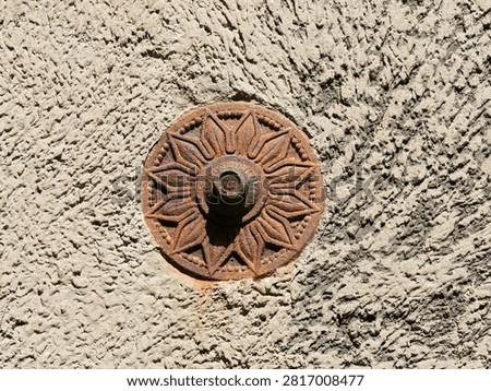 Exposed-rust wall anchor (also known as a wall or purlin anchor) made of cast iron, featuring a decorative flower, sun, or star motif
