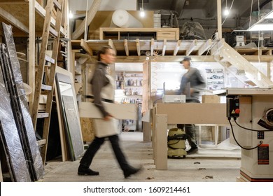Exposure photography two unidentified young employees of small woodworking and furniture industry working on new furniture collection. Concept of own small successful production