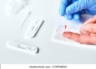 Express COVID-19 test for detection of IgM and IgG antibodies to novel corona virus SARS-CoV-2, Covid-19. Patient finger for analysis. Gloved nurse hand collects blood with disposable pipette.