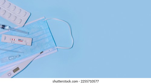 Express Covid-19 XBB.1.5 Kraken Variant strain test,Schnelltest, medical mask, syringe,thermometer,medicine on a blue background.Diagnosis of virus, Inhibition of disease outbreaks.Copy space. - Shutterstock ID 2255710577