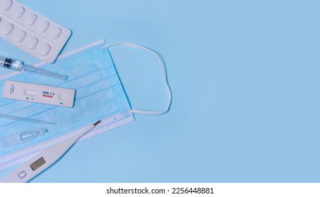 Express Covid-19 XBB.1.5 Kraken Variant strain test,Schnelltest, medical mask, syringe,thermometer,medicine on a blue background.Diagnosis of virus, Inhibition of disease outbreaks.Copy space. - Shutterstock ID 2256448881