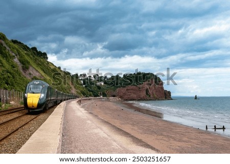 Express train going alongside a beach. Scenic journey along the coast for train  passenger and also coastal walk between Dawlish and Teignmouth. Devon, England , UK