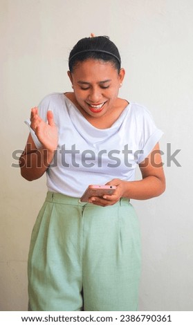 The expression of an Asian woman is happy and surprised when she receives a call and reads a short message