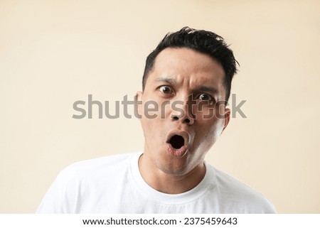 Expression of furious,enraged asian man with grumpy grimace on his face,with mouth opened in shout, ready to argue and swear, wants to gain respect, show strength, isolated over cream background