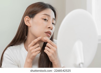 Expression worry asian young woman hand touching pustule around the chin and mouth, allergic when wear mask, makeup, show squeezing pimple spot from face. Beauty care, skin problem by acne treatment. - Shutterstock ID 2268142525