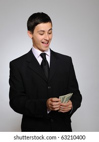 Expressions - Young Handsome Business Man In Black Suit And Tie Counting Money. Gray Background