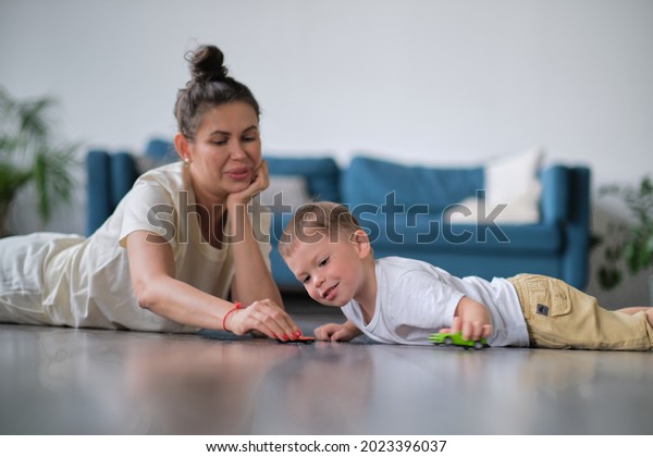 Expressive\
baby boy playing with a toy car with\
mother.