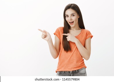 Expressive charming woman discussing new nail salon with girlfriends. Portrait of amazed excited european woman, pointing left with index fingers and saying wow, seeing surprising things