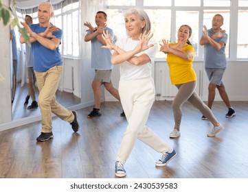 Expressive cheerful woman participating in upbeat Zumba class for group of seniors in mirrored fitness studio.. - Powered by Shutterstock