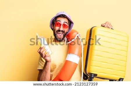 expressive crazy bearded man wearing hat and sunglasses with a suitcase. hollidays concept
