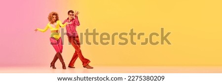 Expressive excited couple of professional dancers in retro style clothes dancing disco dance over pink-yellow background. Concept of 70s, 80s fashion style, music and emotions. banner with copy space
