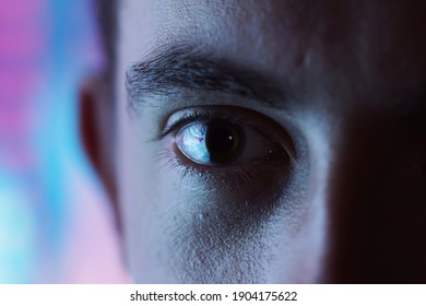 Expressive look - closeup of an eye with blurred blue and pink neon light background and high contrast