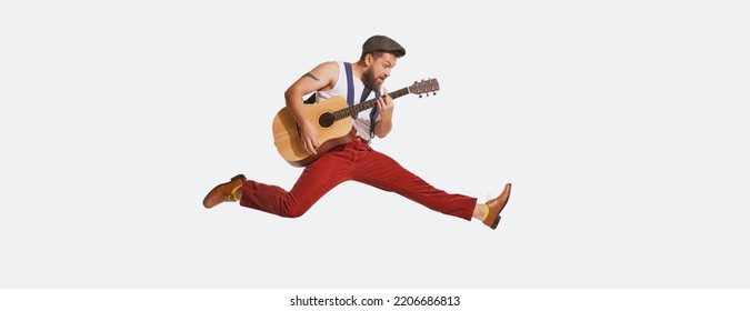 Expressive musician wearing retro style clothes playing guitar like rockstar isolated on white background. Vintage fashion, music, art, emotions, music festiva concept. Copy space for ad