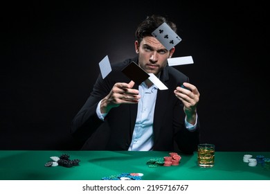 Expressive One Emotional Handsome Caucasian Brunet  Pocker Player At Pocker Table With Chips and Cards While Playing and Drinking Alcohol. Horizontal Image Orientation