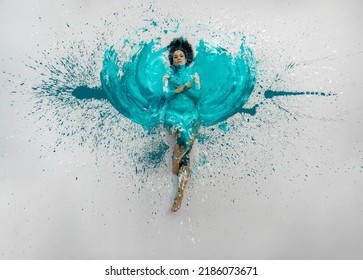 Expressive Sexy Woman Lies Naked Elegant On The Floor In Turquoise Blue Color Abstract Painted Bodypainting Woman On The Splashed Ground, Spreads The Paint In Form Of Angel Wings, Copy Space