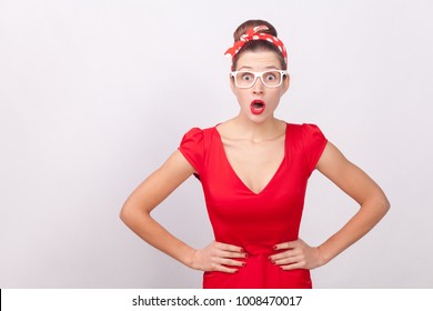 Expressive surprised woman, open mouth with shock, looking at camera. Indoor, studio shot, isolated on gray background