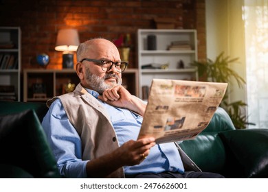 Expresssive Indian asian senior old man reading newspaper at home - Powered by Shutterstock