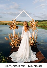 Exquisite bride standing with her back near  wedding arch. Wedding ceremony