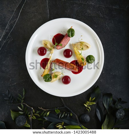 Exquisite Serving Creative Molecular Dish of Duck Breast, Baked Pear and Cherry Spheres Top View. Italian Dish from Chef with Grilled Poultry Fillets on Natural Black Marble Background