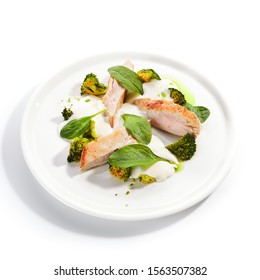 Exquisite Serving Fried Turkey Fillet With Baked Broccoli Cabbage, Spinach Leaves And Cheese Espuma On White Restaurant Plate Isolated. High Cuisine Restaurent Dish With Barbecue Meat Closeup