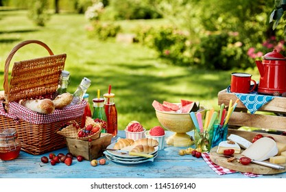 Exquisite summer picnic scene with bread basket, plates of fruit and coffee on table. Includes copy space